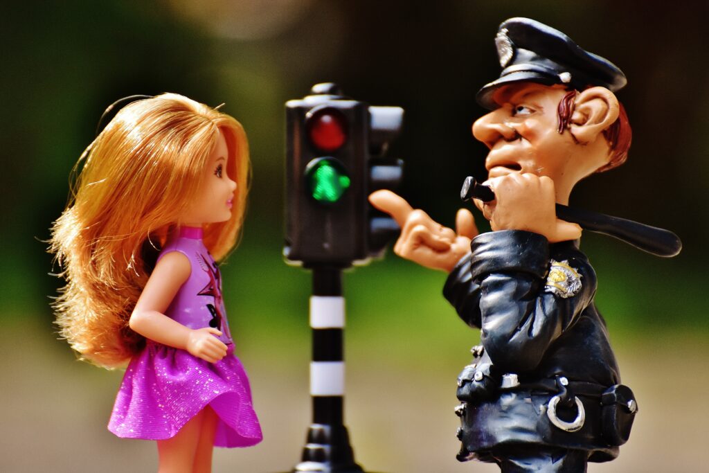 Police figurine pointing at a doll beside a traffic light, illustrating conservatorship restrictions.